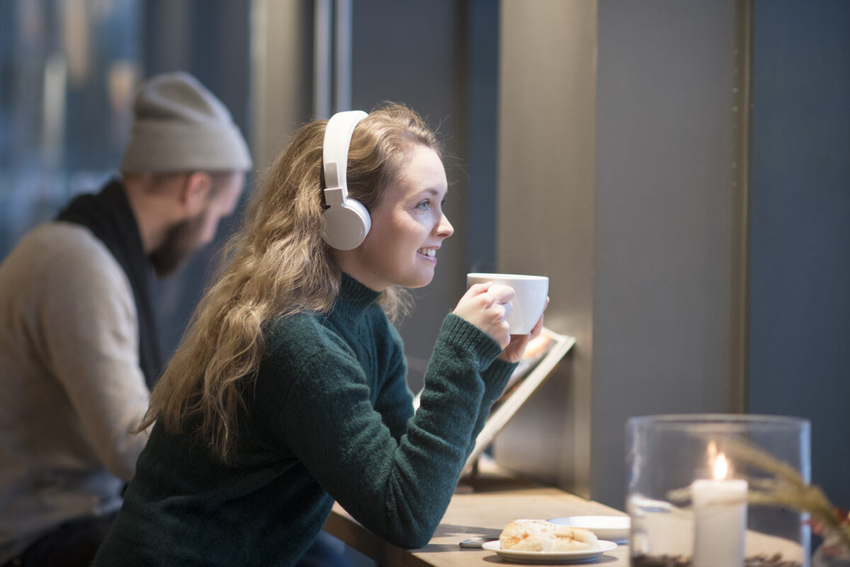 Kvinne med hodetelefoner drikker te og lytter til lydbok